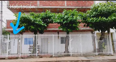 a white fence with trees and a sign on a building at casa Marez in Cartagena de Indias