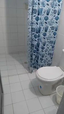 a bathroom with a toilet and a blue and white shower curtain at Cabaña Olas Del Mar in San Bernardo del Viento