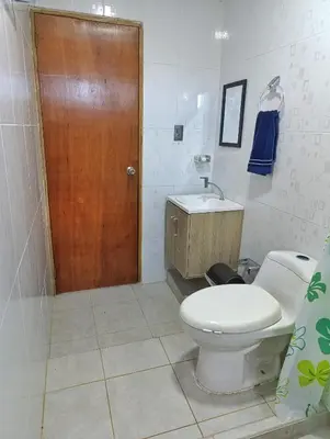 a bathroom with a toilet and a wooden door at Apartamento sereno, cerca al mar in El Porvenir