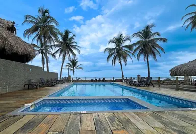 a swimming pool with palm trees on the beach at 203 Apartamento Frente al Mar in San Bernardo del Viento