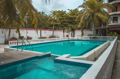 a swimming pool with blue water and palm trees at Hotel Boquilla Suites By GEH Suites in Cartagena de Indias