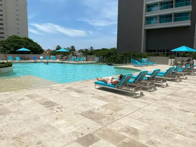 a man laying on a chaise lounge next to a swimming pool at Bello Horizonte Suite in Santa Marta