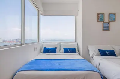 two beds in a room with two windows at Vista de lujo al mar y la bahía in Cartagena de Indias