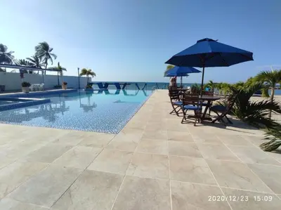 a table and chairs with an umbrella next to a swimming pool at Apartamentos Mi Reserva OK - Bahía Marina in Coveñas