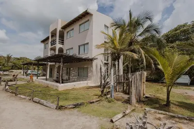a white building with palm trees in front of it at Apartamento Atlantic 311 in La Perdiz