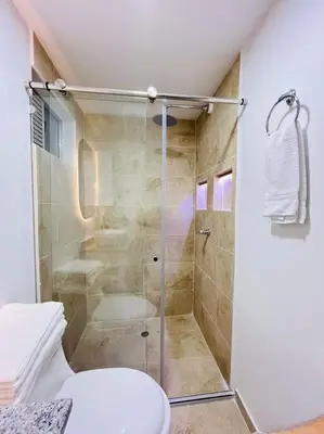 a bathroom with a glass shower with a toilet at Tropical Oasis Barranquilla in Barranquilla
