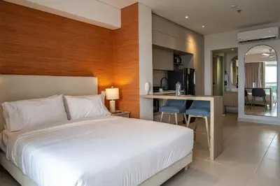a bedroom with a white bed and a kitchen at Hermoso moderno y comodo Cartagena Beach CB741 in Cartagena de Indias