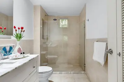 a white bathroom with a toilet and a shower at Walled City apt- Rooftop Pool & Private Garden in Cartagena de Indias