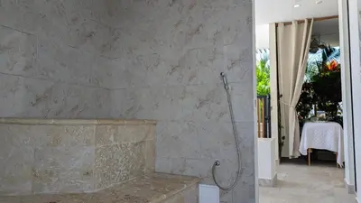 a bathroom with a shower and a stone wall at Piscinas con vista increible, bar, música y playa in Cartagena de Indias