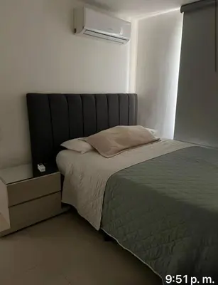 a bed with a gray headboard in a bedroom at Yuyos apartamentos acogedores in Barranquilla