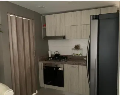 a kitchen with wooden cabinets and a black refrigerator at Yuyos apartamentos acogedores in Barranquilla