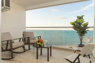 a living room with a table and chairs and a large window at Acogedora suite frente al mar + vista CB1427 in Cartagena de Indias