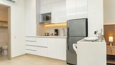 a kitchen with white cabinets and a stainless steel refrigerator at Suite esquina con balcón y vista 180° al mar CB1429 in Cartagena de Indias