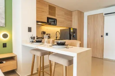 a kitchen with a counter with stools and a table at CB1526 | Suite tropical piso 15 frente al mar in Cartagena de Indias
