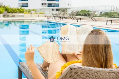 a woman reading a book next to a swimming pool at CB1526 | Suite tropical piso 15 frente al mar in Cartagena de Indias