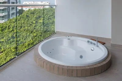 a bath tub in a room with a large window at 2BD Next to Beach W Pvt Jacuzzi Martinique 74 in Cartagena de Indias