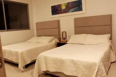 two beds in a room with white sheets at Apartamento en la playa mas tranquila de Cartagena in Cartagena de Indias