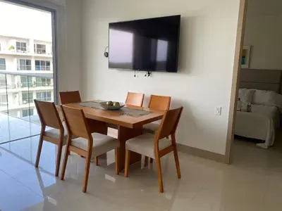 a dining room table with chairs and a television on the wall at Apartamento en la playa mas tranquila de Cartagena in Cartagena de Indias