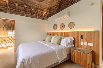 a bedroom with a large bed with a wooden headboard at Islawa Soy Local - Isla Privada in Baru