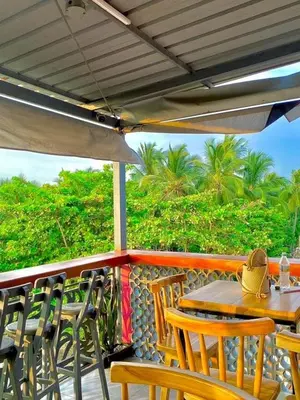 a table and chairs on a porch with an umbrella at Habitación luxury villa oti in Ciénaga