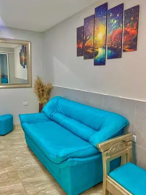a blue couch in a room with paintings on the wall at Habitación luxury villa oti in Ciénaga