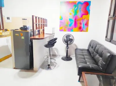 a living room with a black leather couch and a kitchen at Apartamento centro historico 209 in Cartagena de Indias