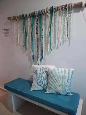a bench with pillows and beads hanging on a wall at Cabañas Ana Sofía in San Antero