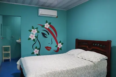 a bedroom with a bed with a painting of a woman at Restaurante y Ecohostal Casa Loma in Chorrera