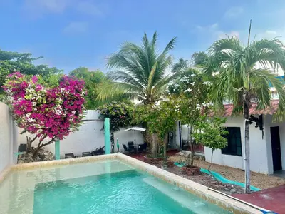 a swimming pool in front of a house with palm trees at Casa Torices Real 12 in Cartagena de Indias