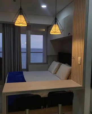 a bedroom with a bed with two chairs and a window at Apartamento con vista al mar in Cartagena de Indias