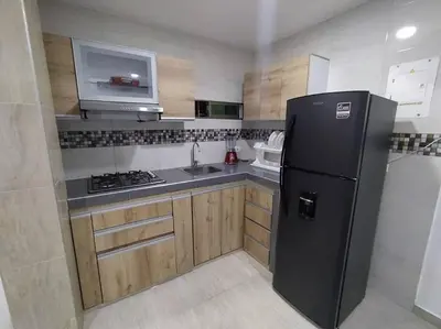 a kitchen with a black refrigerator and a sink at Apto 202, área mtana de Barranquilla in Soledad