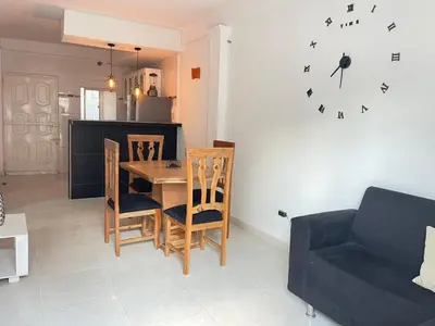 a living room with a table and chairs and a clock at Apto céntrico torices 1 piso 2 habitaciones in Cartagena de Indias