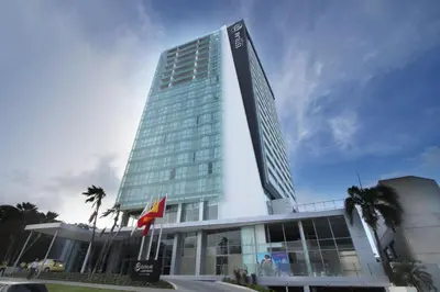a tall building with palm trees in front of it at Apartamento Hotel estelar in Barranquilla