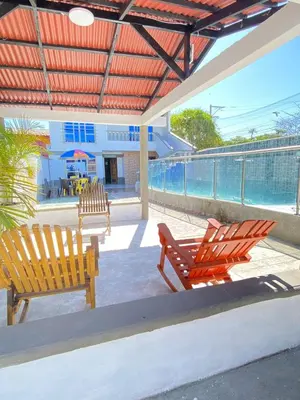 two wooden chairs sitting on a patio with a pool at Cabaña Tolu in Santiago