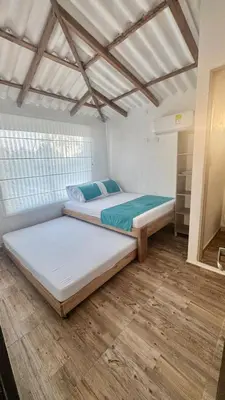two beds in a room with wooden floors at Hermosa Cabaña Frente Al Mar in San Bernardo del Viento