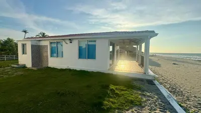 a white house on the beach with the ocean at Hermosa Cabaña Frente Al Mar in San Bernardo del Viento