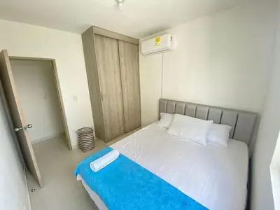 a small bedroom with a bed with a blue blanket at Vista panoramica al Mar y Piscina in Cartagena de Indias
