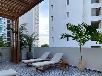 a patio with two lounge chairs and a palm tree at San Martin by Wynwood House in Cartagena de Indias
