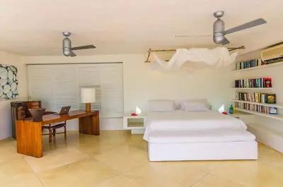 a bedroom with a bed and a desk with a laptop at Villa Los Cocos Baru in Baru