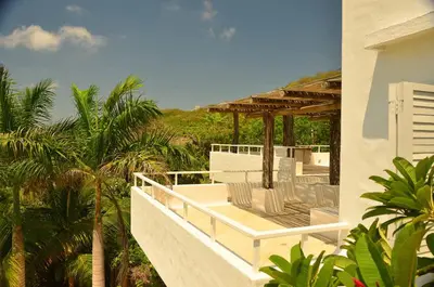 a balcony of a house with chairs and trees at Villa Los Cocos Baru in Baru