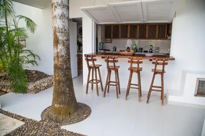a kitchen with a bar with stools and a tree at Villa Los Cocos Baru in Baru