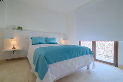 a bedroom with a bed with blue pillows and a window at Hotel Boutique La Artilleria in Cartagena de Indias