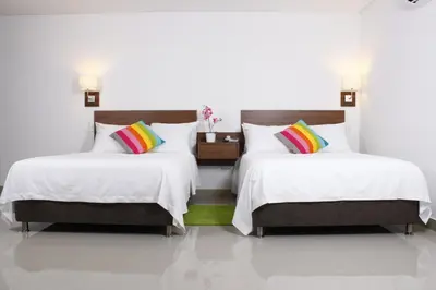 two beds in a room with white walls and white floors at Hotel Soleira in Tolú