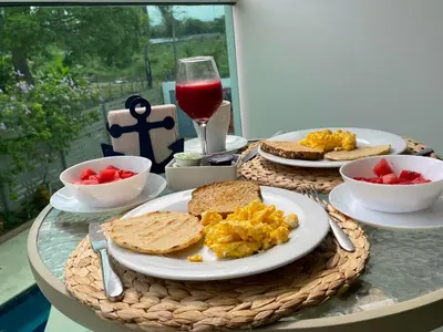 a breakfast table with eggs and toast and a glass of wine at Hotel Soleira in Tolú