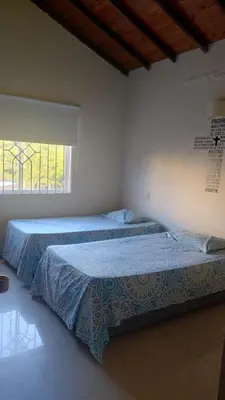 two beds in a white room with a window at Habitación Canarios in Barranquilla