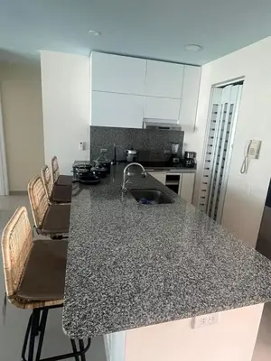 a kitchen with a counter with chairs and a sink at Lux Oceanfront Apartment in Cartagena de Indias