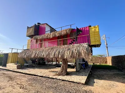 a building with a straw roof on the side of it at Surf Mojarra Beach Habitación privada con vista al mar in Salina de Rey