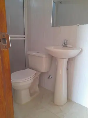 a white bathroom with a toilet and a sink at Cabaña frente al mar de San Antero in San Antero