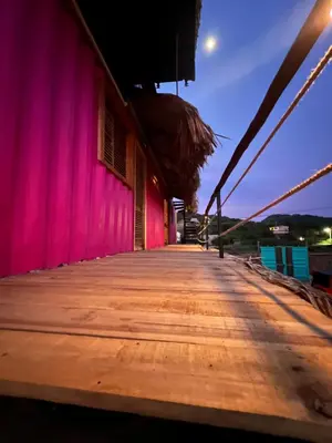 a wooden boardwalk leading to a pink building at Love en Mojarra Beach Habitación privada vista al mar in Salina de Rey