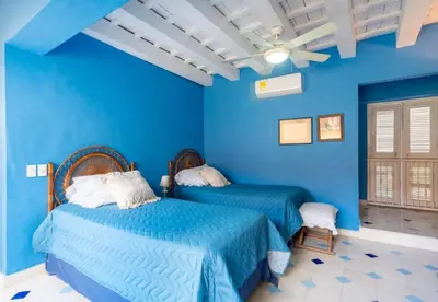 a blue bedroom with two beds and a ceiling fan at Casa azul in Cartagena de Indias